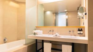 墨西哥城NH系列墨西哥城机场T2航站楼酒店的浴室设有2个水槽、镜子和浴缸。