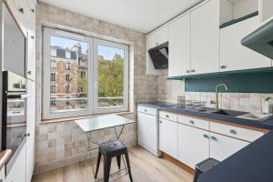 塞夫尔Appartement elegant- Parc Saint Cloud的厨房配有白色橱柜、桌子和2扇窗户。