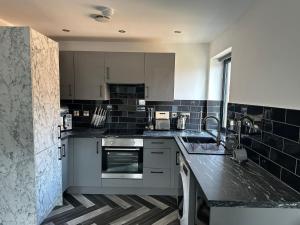 彼得伯勒Newark House Premium Apartments by DH ApartHotels的厨房配有白色橱柜和黑色瓷砖