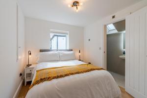 切尔滕纳姆Norton Coach House的白色的卧室设有一张大床和一个窗户