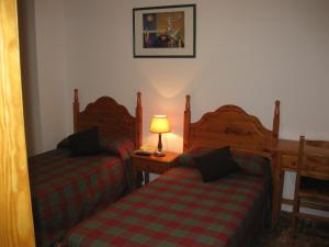 AlboreaHostal Alvaro I的一间卧室设有两张床和一张桌子上的台灯。