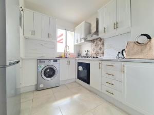 卡博尼格洛Superbe appartement avec une vue panoramique sur piscine的厨房配有白色橱柜和洗衣机。