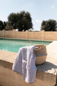 法萨诺Casale degli Ulivi by Apulia Hospitality的游泳池旁的篮子上一条毛巾