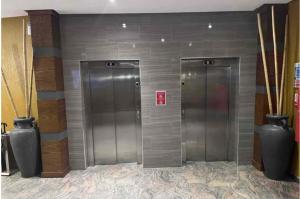 库马西Wynn Apt - Luxe / Uninterrupted Power / Near Mall / Sleeps 3的一座带花瓶的建筑里两部银色电梯