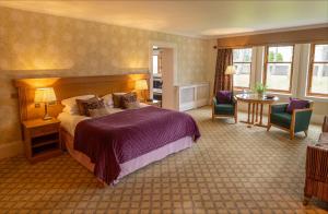 LoansLochgreen House Hotel & Spa的酒店客房带一张床、一张桌子和椅子