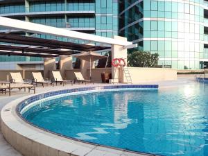 迪拜Frank Porter - Marsa Plaza的一座带椅子的游泳池以及一座建筑