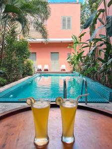 科伦坡Angam Villas Colombo的两杯啤酒坐在游泳池旁的桌子上