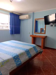 MacutoHotel El Ceibo的一间卧室配有一张床、镜子和电视