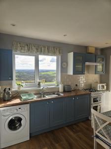 哈佛威斯特Meadow cottage的厨房配有蓝色橱柜、水槽和窗户。