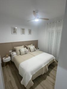 卡莫纳Apartamento Vitelio的白色卧室设有一张大床和吊扇