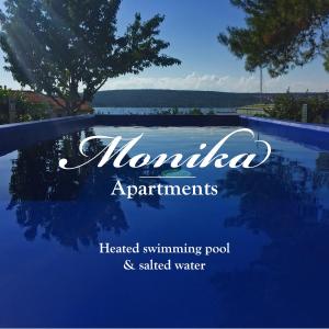 普纳特Apartments Monika Bed & Breakfast的一个读诺米尼亚温水游泳池和高水公寓的标志