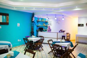 圣若昂-巴蒂斯塔-杜格罗里亚Pousada Encantos do Glória的一间设有桌椅的餐厅,位于拥有蓝色墙壁的房间