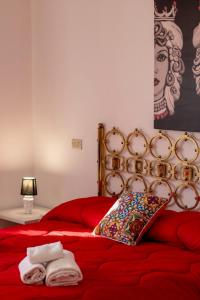 陶尔米纳SUITE APARTMENT TAORMINA的红色的床,上面有枕头和毛巾