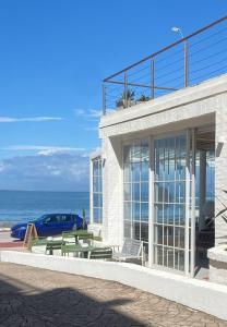埃斯特角城Vitaminas - Casa de Playa y Café的一座带桌子和长凳的海洋前方建筑