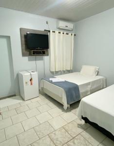 托坎廷斯州圣费利克斯Pousada Capim Dourado Jalapão São Felix TO的客房设有两张床和一台平面电视。