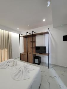 卡萨米尔Prestige Hotel的卧室配有白色的床和电视。