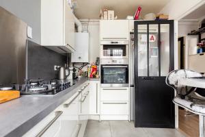 欧奈索斯博伊斯Chbre 2P + navette CDG的厨房配有白色橱柜和黑色冰箱。