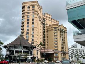 古晋Cozzzy hut Riverbank Suites Kuching with spectacular River view的一座高大的建筑,前面有一个凉亭