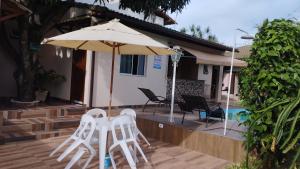 瓜拉派瑞Casa c/ Piscina e Área Gourmet, 5 min da praia.的庭院配有两把白色椅子和遮阳伞