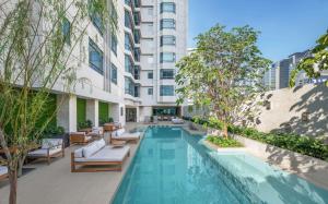 曼谷曼谷奔集路希尔顿逸林酒店的一座带躺椅和树木的无边游泳池
