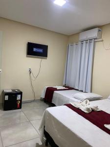 伦索伊斯Pousada Vista da Serra - Suzart的客房设有两张床和一台墙上的电视。