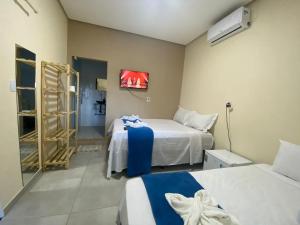 伦索伊斯Pousada Vista da Serra - Suzart的客房设有两张床和一台墙上的电视。