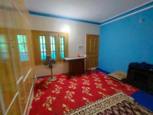 LamniānSharian Guest House的一间卧室,铺有红地毯,拥有蓝色的墙壁