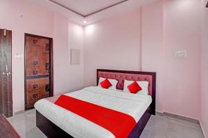 那格浦尔OYO Flagship Hotel Anand In的一间卧室配有一张带红色枕头的大床