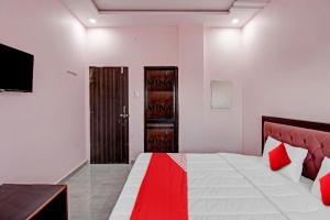 那格浦尔OYO Flagship Hotel Anand In的一间卧室配有一张带红白毯子的床