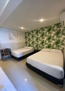 圣安德烈斯Apartahotel Marbella的一间卧室设有两张床,墙上有植物