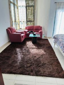 阿吉曼Tranquil Haven:King Bed, Ensuite, Master Bedroom的客厅配有红色沙发和棕色地毯