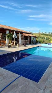 林多亚Pousada irmãos Oliveira的房屋前方设有蓝色瓷砖地板的游泳池