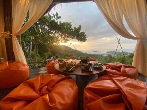 Ban KataGreenheart garden View Camp phuket的配有橙色椅子和桌子的房间以及窗户