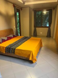 达累斯萨拉姆Zanzibar in Dar! A newly renovated 3br villa的一间卧室配有一张黄色棉被的床