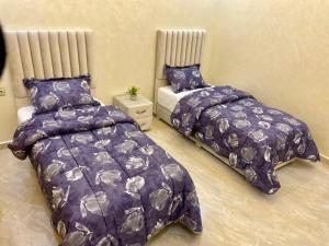 胡塞马Appartement pour famille avec enfant的卧室内的两张床和紫色棉被
