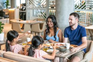 玛志洛Holiday Inn Express & Suites Sunshine Coast, an IHG Hotel的坐在餐桌旁吃饭的家庭