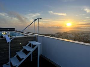 梅利哈Private Pool For Your Holiday In Mellieha的阳台设有梯子,享有日落美景。