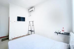 贝克西Citara Jaya Guesthouse Mitra RedDoorz的白色的客房配有床和电视。