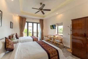 会安Rice River Villa - Hoi An的酒店客房设有两张床和一张桌子。