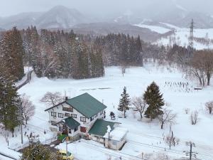Chikuniロッヂ秀岳的雪中带绿色屋顶的房子