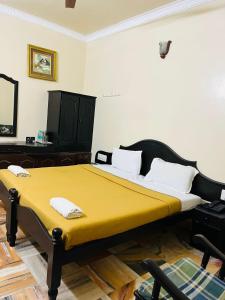 马迪凯里Coorg HillTown Hotel - Madikeri的一间卧室配有一张带黄色毯子的大床