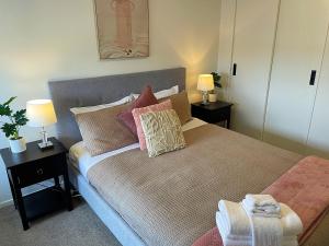 奥克兰布什假期住宿公寓的一间卧室配有一张带枕头的床和两盏灯。