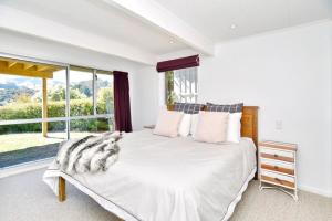阿卡罗阿Akaroa Harbour View - Christchurch Holiday Homes的卧室配有白色的床和大窗户