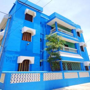 普里Hotel J K Inn Puri Near Sea Beach的前面有棵树的蓝色建筑