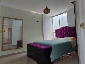 伊察Casa Piscina Duna Saraja Ica-Perú的一间卧室配有一张紫色的床和镜子