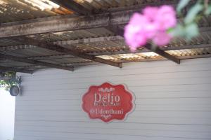 乌隆他尼Delio Boutique Hotel的车库边有粉红色花的标志