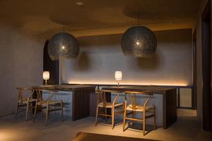箱根nol hakone myojindai的酒吧配有椅子和2张桌子及2盏灯