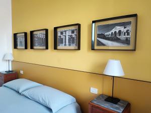 曼托瓦Foresteria Juvarra的卧室配有一张床,墙上挂有四张照片