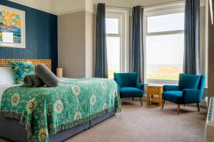 克罗默三德克里夫旅馆的一间卧室配有一张床和两张蓝色椅子