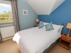 哈佛威斯特The Annexe, Meadow Croft的卧室配有白色的床、蓝色的墙壁和窗户。
